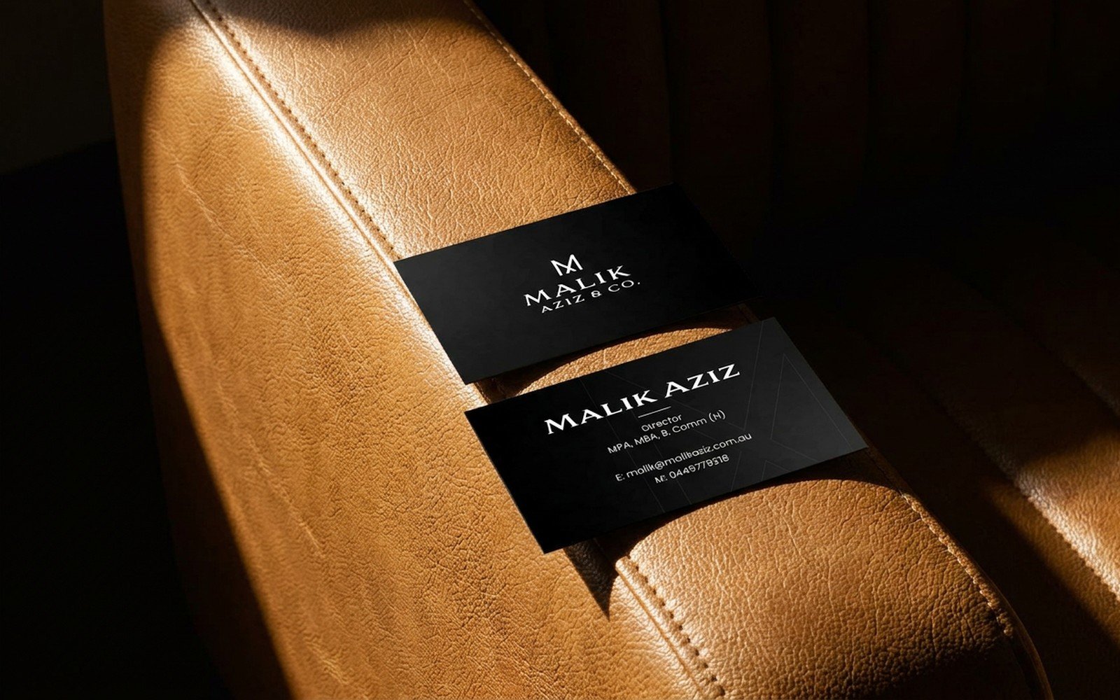 Front and back of the Malik Aziz and Co. business card on a leather armchair