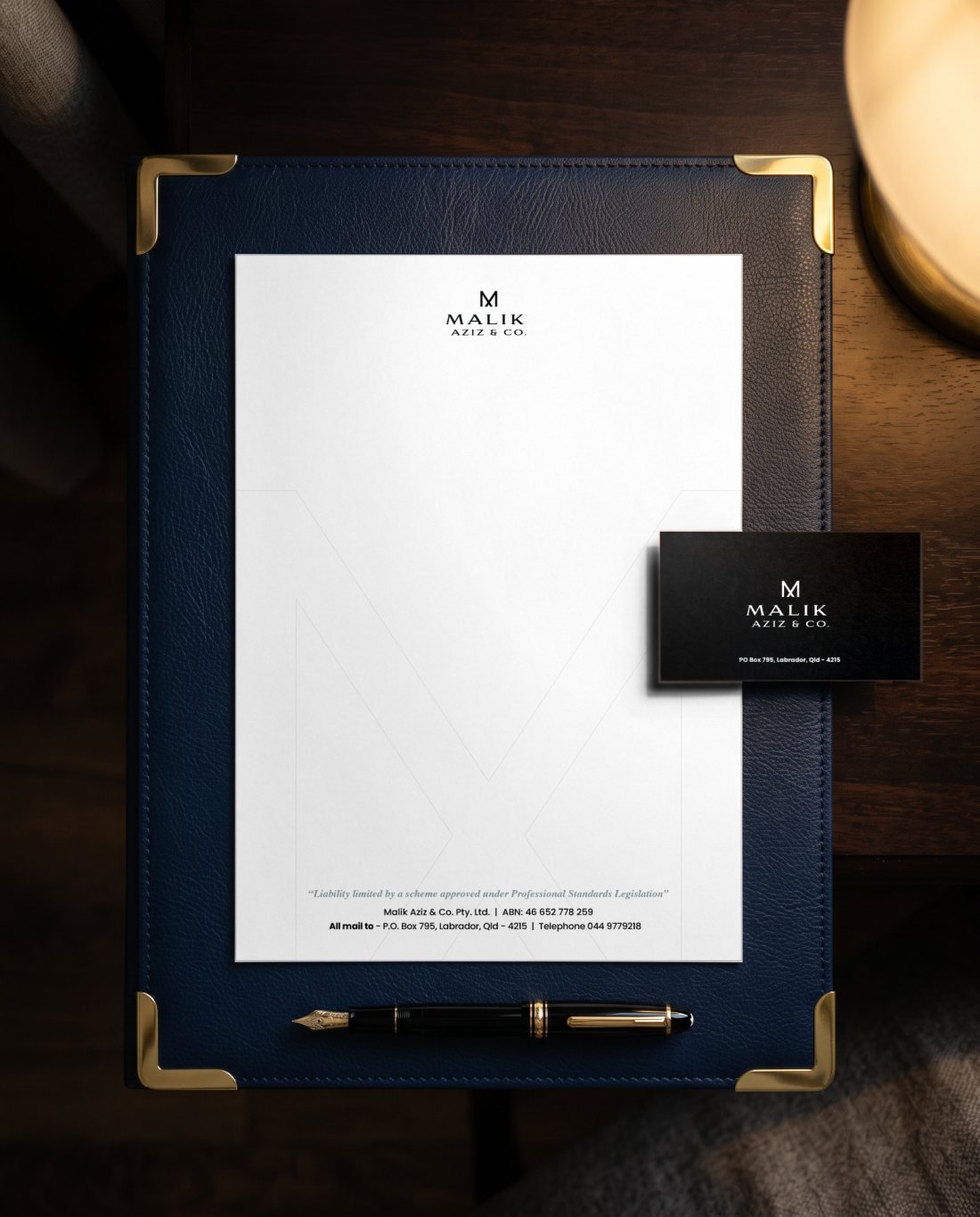 Malik Aziz and Co. letterhead and business card on a navy leather desk blotter with a fountain pen