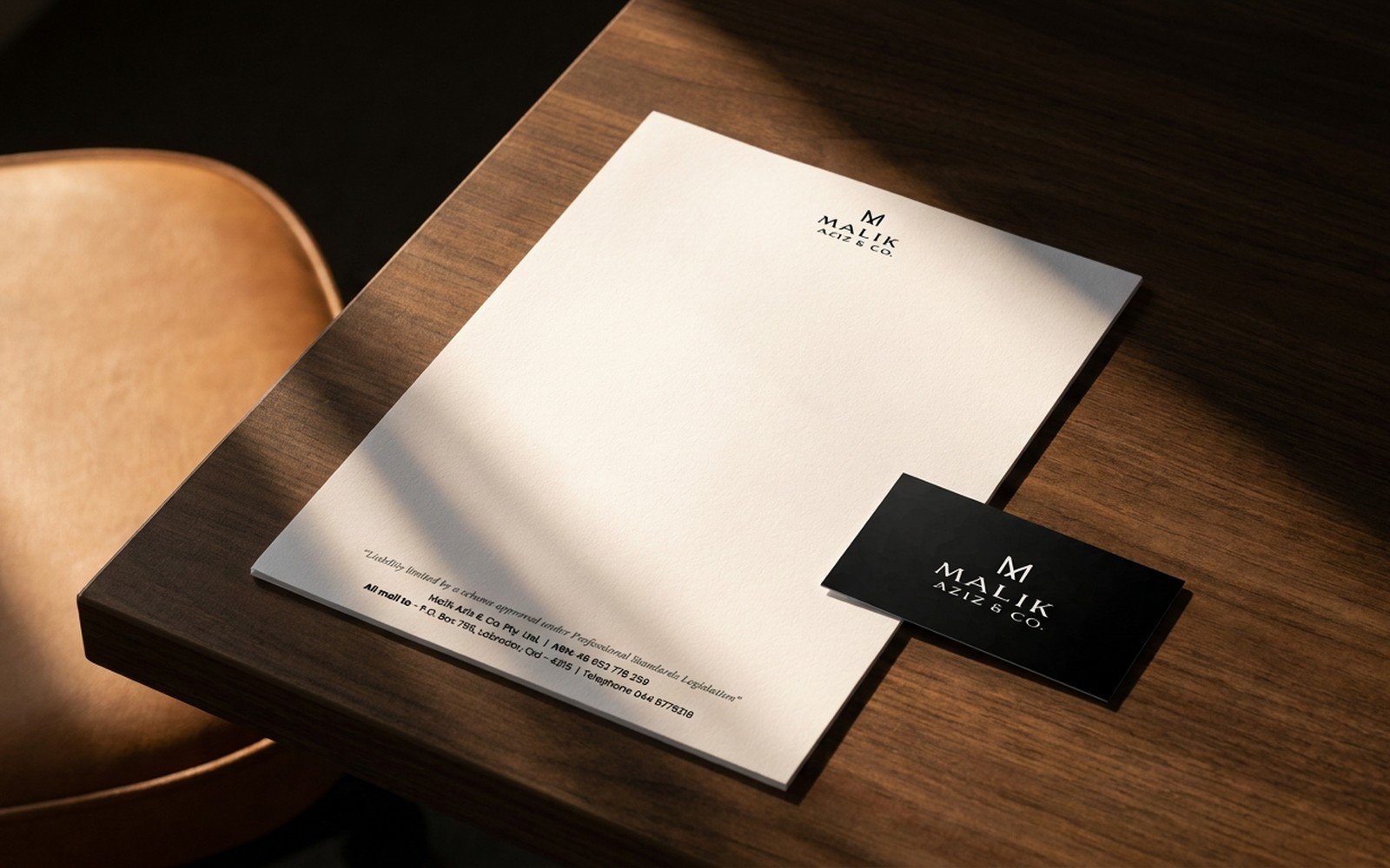 Malik Aziz and Co. letterhead and business card on a walnut desk